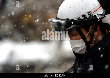 Ein Mitglied mit dem japanischen Search and Rescue Team durchsucht den Schaden und die Trümmer am 17. März 2011, in Unosumai, Japan Stockfoto