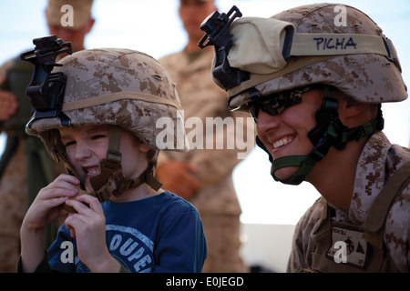 Lance Cpl. Don Picha, rechts, 2. Bataillon, 7. Marineregiment, posiert für ein Foto mit einem Kind nach ließ ihn anprobieren Stockfoto