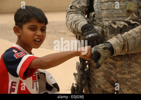 Ein kleiner Junge Pfund Fäuste mit einem US-Soldaten außerhalb der Huda Mädchenschule in Tarmiyah, Irak, Juli 29. Stockfoto