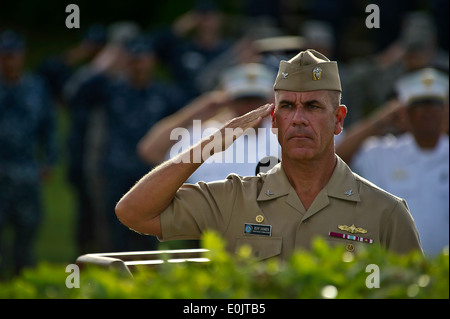 US Navy Captain Jeffery James, gemeinsame Basis Pearl Harbor-Hickam Kommandant salutiert, wie die amerikanische Flagge, die Hälfte Mitarbeiter ausgelöst wird ein Stockfoto