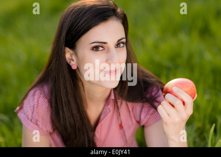 Frau mit Apfel auf Wiese, (Model Release) Stockfoto