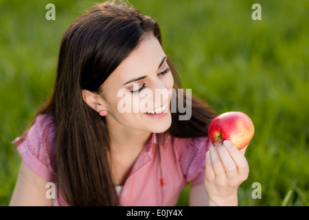 Frau mit Apfel auf Wiese, (Model Release) Stockfoto