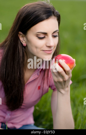 Frau mit Apfel auf Wiese, (Model Release) Stockfoto