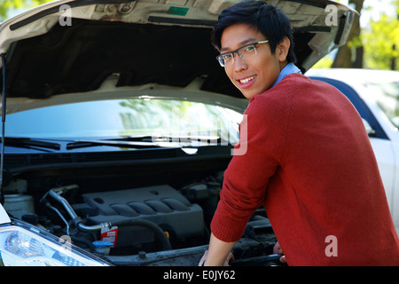 Junge asiatische glücklich Überprüfung seiner Automotor Stockfoto