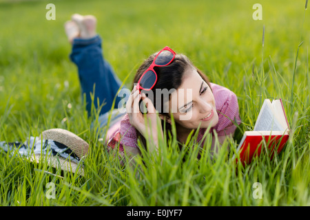 Frau liegend mit Buch auf Wiese, (Model Release) Stockfoto