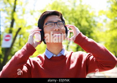Junge asiatische glücklich anhören von Musik im park Stockfoto