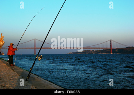 Fischen bei Sonnenuntergang auf den Fluss Tejo (Tejo) mit Denkmal der Entdeckungen und 25. April Brücke Lissabon Portugal Westeuropa Stockfoto