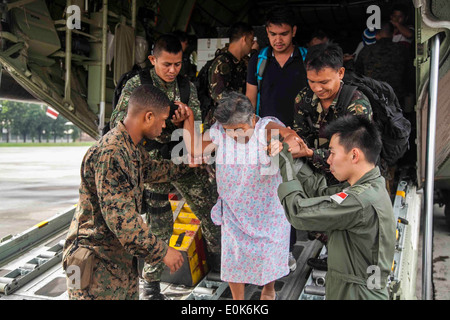 U.S. Marine Lance Cpl. Xavier L. Cannon und Mitglieder der philippinischen Streitkräfte unterstützen Zivilisten aus einer c-130 Flugzeuge Nov. Stockfoto