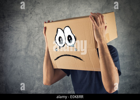 Mann mit Karton auf den Kopf und traurig weinende Gesichtsausdruck. Konzept der Traurigkeit und Depression. Stockfoto