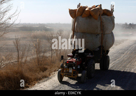 Ein afghanischer Staatsangehöriger treibt seinen schwer beladenen Traktor neben eine berittene Patrouille (nicht gezeigt) unter der Leitung von Marine der persönlichen Stockfoto