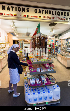 Religiöse Symbole, Weihwasser und Statuen zum Verkauf an Souvenirläden an Wallfahrtsort Lourdes in Südfrankreich Stockfoto