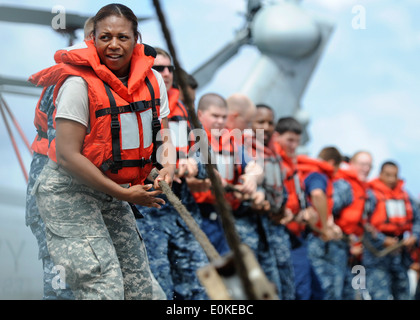 SPC. Tracey Hargroves hilft Haul in Linien während einer Auffüllung auf hoher See an Bord der amphibischen Transportschiff der Dock USS Cleveland Stockfoto
