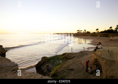 Menschen Sie hängen auf den Klippen und genießen Sie den Ausblick wie Strandurlauber den Sonnenuntergang entlang Steamers Lane in Santa Cruz, Kalifornien genießen Stockfoto