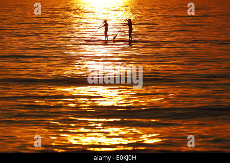 San Diego, CA, USA. 15. Mai 2014. 15. Mai 2014 gleiten - San Diego, Kalifornien, USA - Paddleboarders über den Ozean, wie Rauch aus den letzten Waldbrände in San Diego County einen orangenen Sonnenuntergang sorgt. Bildnachweis: KC Alfred/ZUMAPRESS.com/Alamy Live-Nachrichten Stockfoto