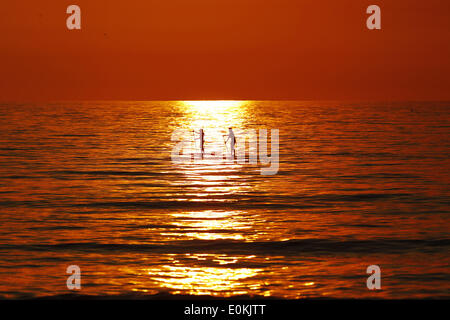 San Diego, CA, USA. 15. Mai 2014. 15. Mai 2014 gleiten - San Diego, Kalifornien, USA - Paddleboarders über den Ozean, wie Rauch aus den letzten Waldbrände in San Diego County einen orangenen Sonnenuntergang sorgt. Bildnachweis: KC Alfred/ZUMAPRESS.com/Alamy Live-Nachrichten Stockfoto