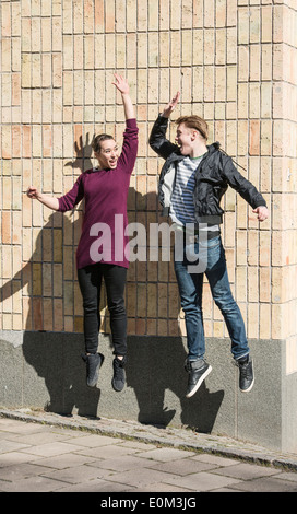 Junger Mann und Frau springen und dabei einen hohen fünf Gruß Stockfoto