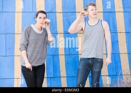 Junger Mann und Frau in einer Blechdose Telefon Konzeptbild zeigen Mangel an Kommunikation und hören in einer Beziehung hören Stockfoto