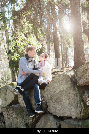 Junges Paar in der Natur auf den großen Felsen in Wäldern während einer Wanderung ausruhen. Sitzt auf der Kante halten sie einander. Stockfoto