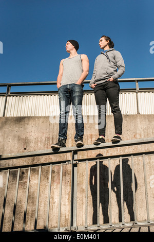Porträt von lockeren und entspannten junger Mann und Frau balancieren auf Schiene im Stadtgebiet. Stockfoto