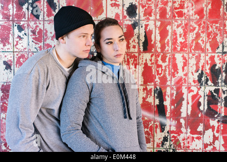 Porträt des lockeren und entspannten junger Mann und Frau wartet vor Graffiti-Wand im Stadtgebiet. Stockfoto