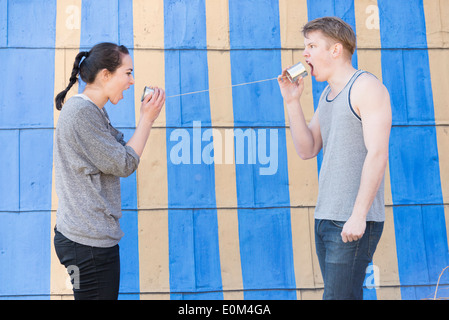 Junger Mann und Frau schreiend in einer Blechdose Telefon Konzeptbild zeigen von Wut und Frustration in einer Beziehung. Stockfoto