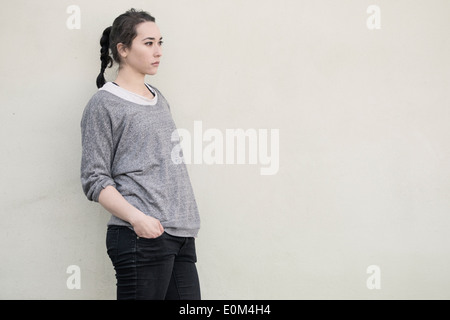 Porträt des jungen spanischen Frau stand vor Wand. Nachdenklichen Ausdruck und wegsehen. Stockfoto