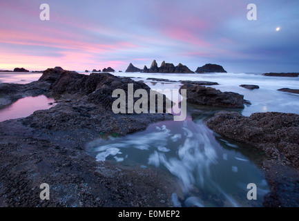 Ein Vollmond legt fest, wie die Sonne über die erstaunliche Felsformationen, Seal Rocks State Park, Oregon, USA Stockfoto