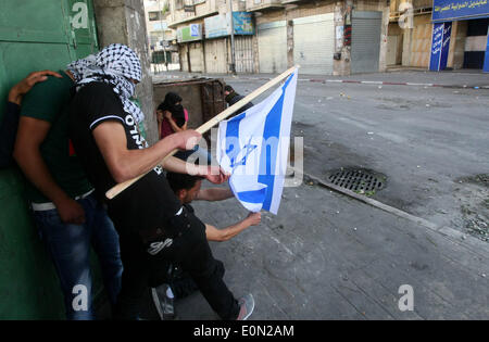 Hebron, Westjordanland, Palästinensische Gebiete. 16. Mai 2014. Palästinensische Demonstranten verbrennen eine israelische Flagge bei Zusammenstößen mit israelischen Truppen nach einer Kundgebung zur Solidarität mit den palästinensischen Gefangenen in israelischen Gefängnissen, in der West Bank von Hebron 16. Mai 2014 statt. Rund 120 Palästinenser ohne Gerichtsverfahren in Israel inhaftiert wurden auf einen unbefristeten Hungerstreik, Essen nur Salz und Trinkwasser, für die letzten 23 Tage fordern ein Ende der so genannten '' Verwaltungshaft © Mamoun Wazwaz/APA Images/ZUMAPRESS.com/Alamy Live News Stockfoto