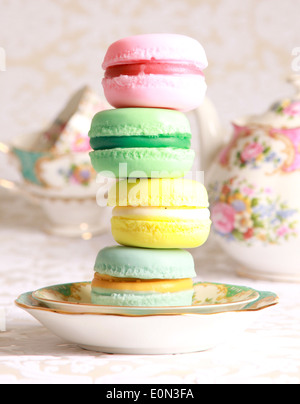 Vier übereinander Macarons auf eine Tee-Untertasse mit Teetassen im Hintergrund. Stockfoto