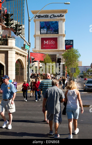 Fußgänger, die unter dem Schild zum Hotel in Monte Carlo und Kasino auf dem Las Vegas Boulevard (dem Strip) spazieren Stockfoto