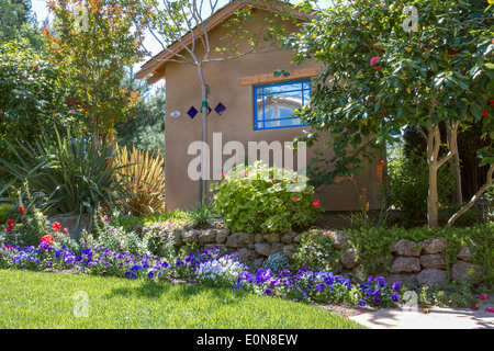 Südwestliche Art Schuppen zwischen Blumen und üppiger Vegetation in einem schönen begrünten Hinterhof-Garten Stockfoto