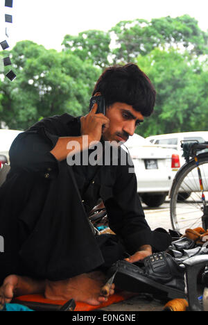 (140517)--ISLAMABAD, 17. Mai 2014 (Xinhua)--A Schuh-Hersteller Gespräche über sein Handy über Welt Telekommunikation und Gesellschaft-Infotag in Islamabad, der Hauptstadt von Pakistan am 17. Mai 2014. Welt-Telekommunikation und Gesellschaft-Info-Tag soll zum Gedenken an die Gründung der International Telecommunication Union am 17. Mai 1865, und markieren Sie ihre Rolle in der Welt zu verbinden. (Xinhua/Saadia Seher) Stockfoto