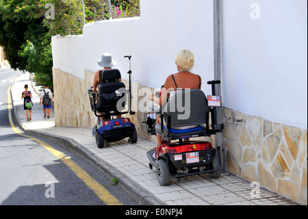 Zwei Frauen auf gemieteten Elektro-Roller Mobilität auf Pflaster von Los Cristinos, Teneriffa Stockfoto