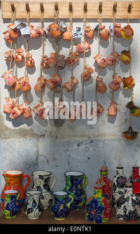 Bunte Steinzeug Souvenirs mit Eidechsen und bemalte Krüge aus Keramik auf dem Display gegen eine weiße Steinmauer. Stockfoto