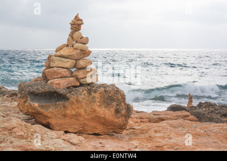 Steinfigur am Meer mit Wellen, Licht und Wolken durch den Horizont. Mallorca, Balearen, Spanien im Oktober. Stockfoto