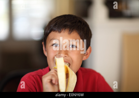 Eine junge Schuljunge genießt Essen eine Banane - sehr geringe Schärfentiefe mit Textfreiraum Stockfoto