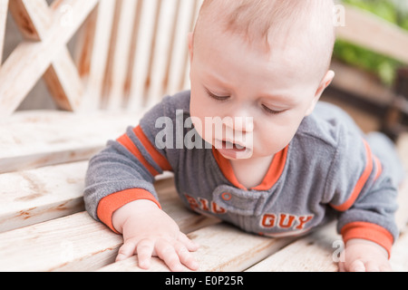 Niedliche Baby Boy Spielen auf der Bank in einem Park. Stockfoto