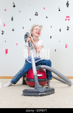 Niedliche kleine Mädchen singen während der Reinigung der Wohnung. Stockfoto