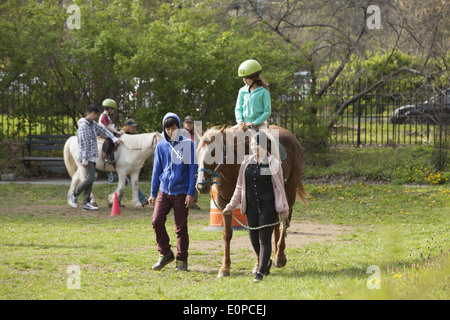 Behinderte Kinder erhalten Entwicklungs-Therapie, bekannt als Hippotherapie Reiten lernen. Prospect Park in Brooklyn, NY Stockfoto