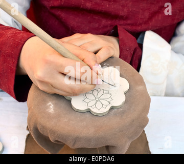 Handwerker Gravur floralen Motiv der keramischen Fliese. Selektiven Fokus Hände Stockfoto