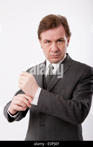 Mann in einem grauen klassischen Business Anzug sein Hemd Manschette, vor einem weißen Hintergrund anpassen. Stockfoto