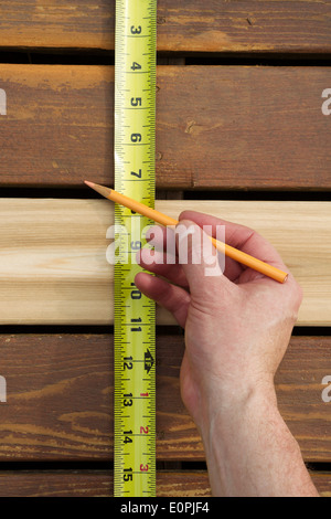 Vertikale Foto von Hand mit Bleistift und Band Messen Abstand zwischen neuen Zeder Holzplatten auf hölzernen Terrasse Stockfoto