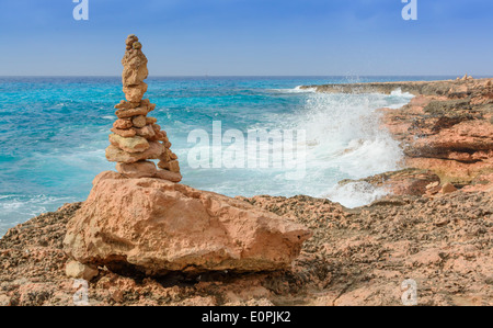 Rock-Turm, Cairn und plätschernden Wellen am Cap de ses Salines, Süden Mallorcas. Mallorca, Balearen, Spanien. Stockfoto