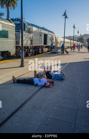 Ein Mann und eine Frau liegend auf dem Bahnsteig beim warten auf des Anrufs, einen Amtrak-Zug in Santa Barbara, Kalifornien. Stockfoto