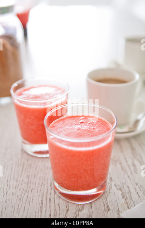 Nahaufnahme von zwei Gläser Erdbeer-Smoothies mit Tasse Kaffee im Hintergrund Stockfoto