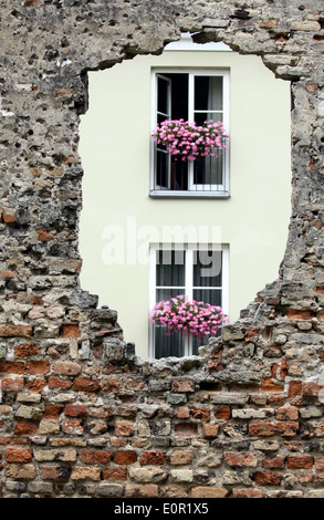 Schauen Sie sich das neue Gebäude durch das Loch in der alten Backsteinmauer Stockfoto