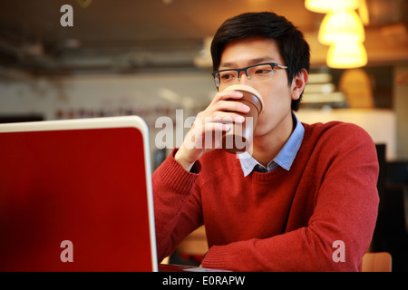Junge asiatische Mann am Laptop arbeiten und Kaffee trinken Stockfoto