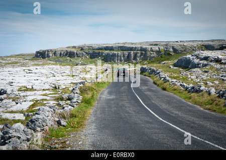 Auto in der Ferne verschwindet auf der Touring Route durch den Burren im County Clare Wilde Atlantik unterwegs an der Westküste von Irland Stockfoto