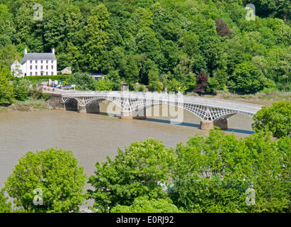 Blick auf die Regency Gusseisen Old Wye Bridge über den Fluss Wye in Chepstow, Wales neben einem großen weiß bemalten Haus, umgeben von Bäumen im Blatt Stockfoto