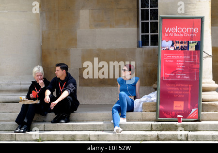 London, England, Vereinigtes Königreich. Leute sitzen auf den Stufen des All Souls Church, Langham Place, Regent Street Stockfoto